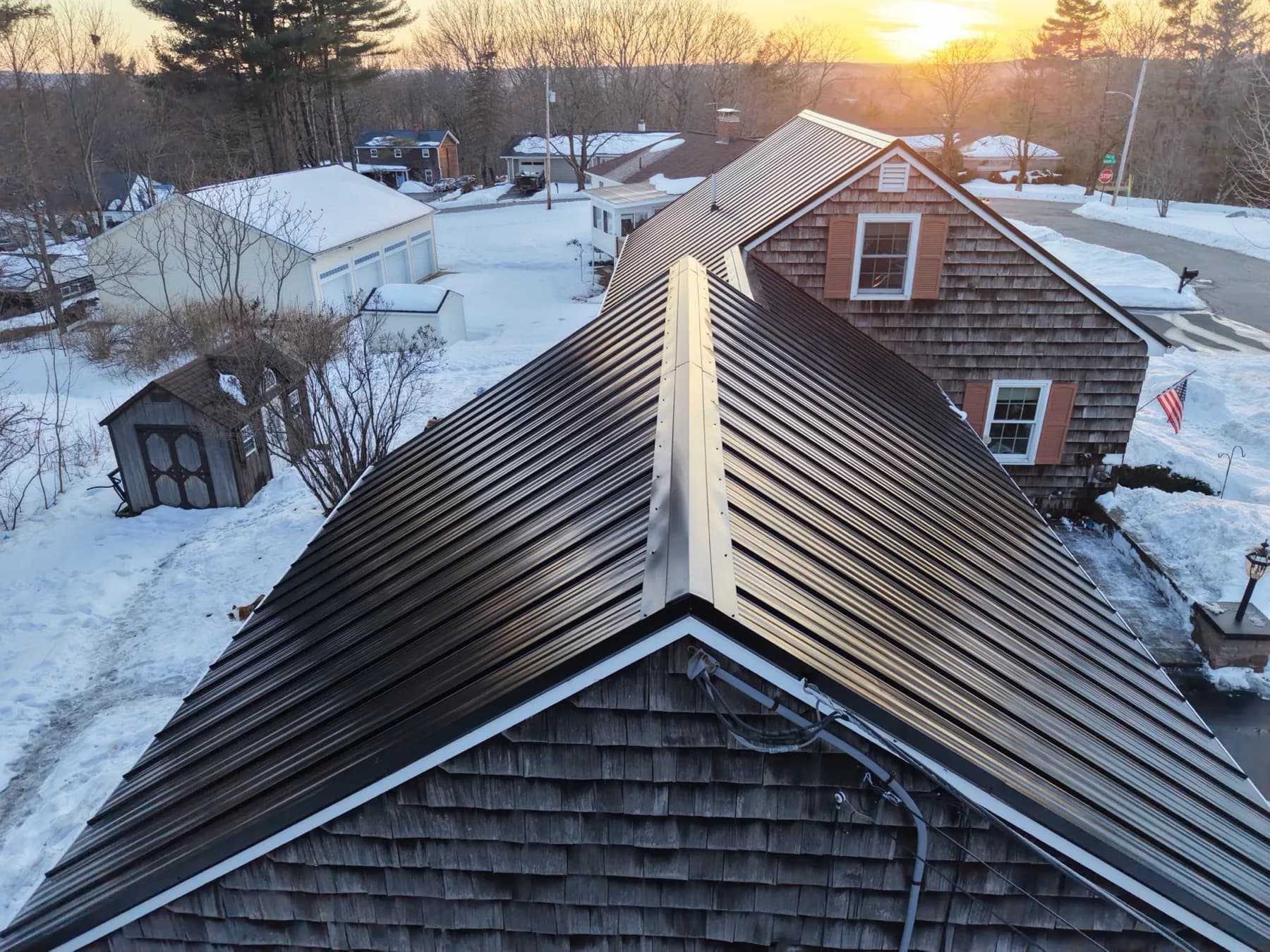 Completed standing seam metal roof project photographed at sunset in Southern Maine