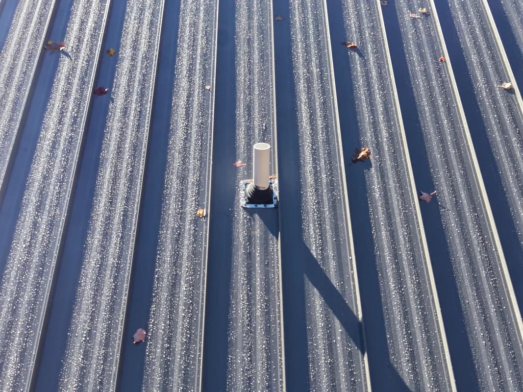 Standing seam metal roof with chimney flashing detail - professional installation in Maine